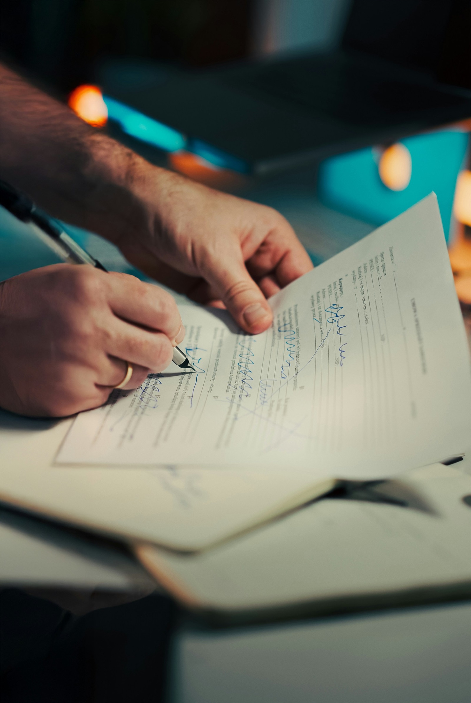 Close-up of hands signing a printed contract with a pen