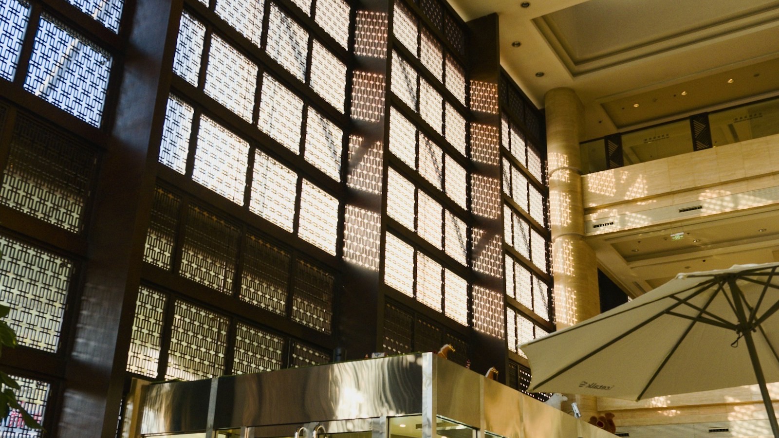 A grand, warmly lit hotel lobby atrium with a dramatic latticed light wall