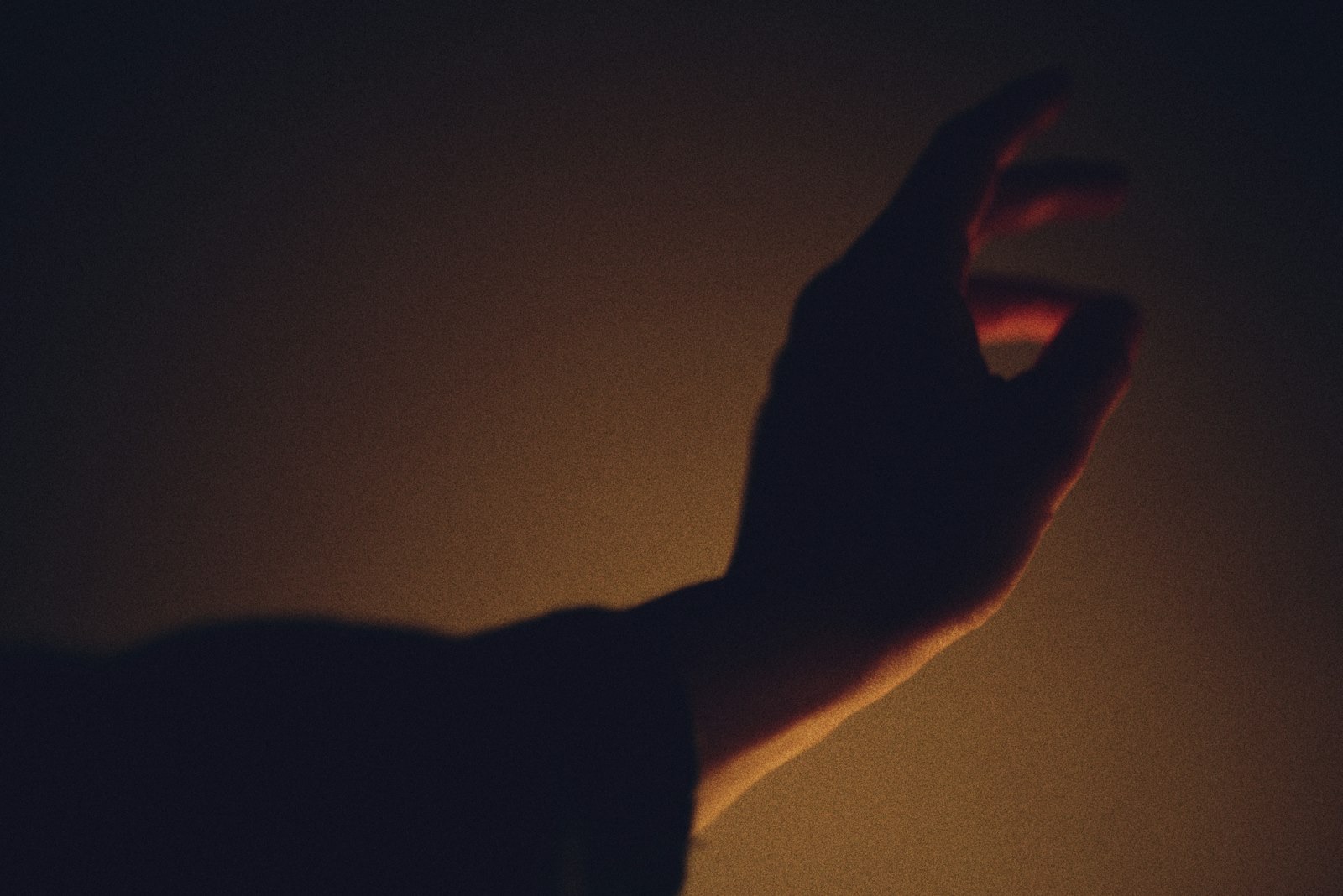 Hand silhouette gesturing against a dark background