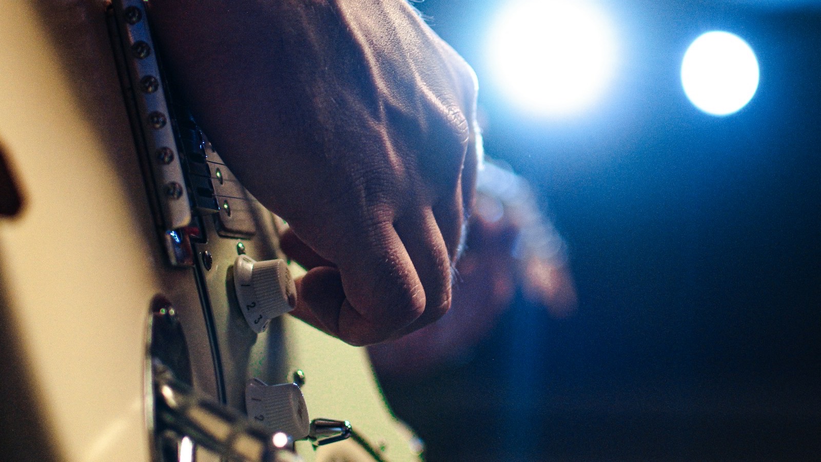 Close-up of a guitarist's hand on an electric guitar under stage lights