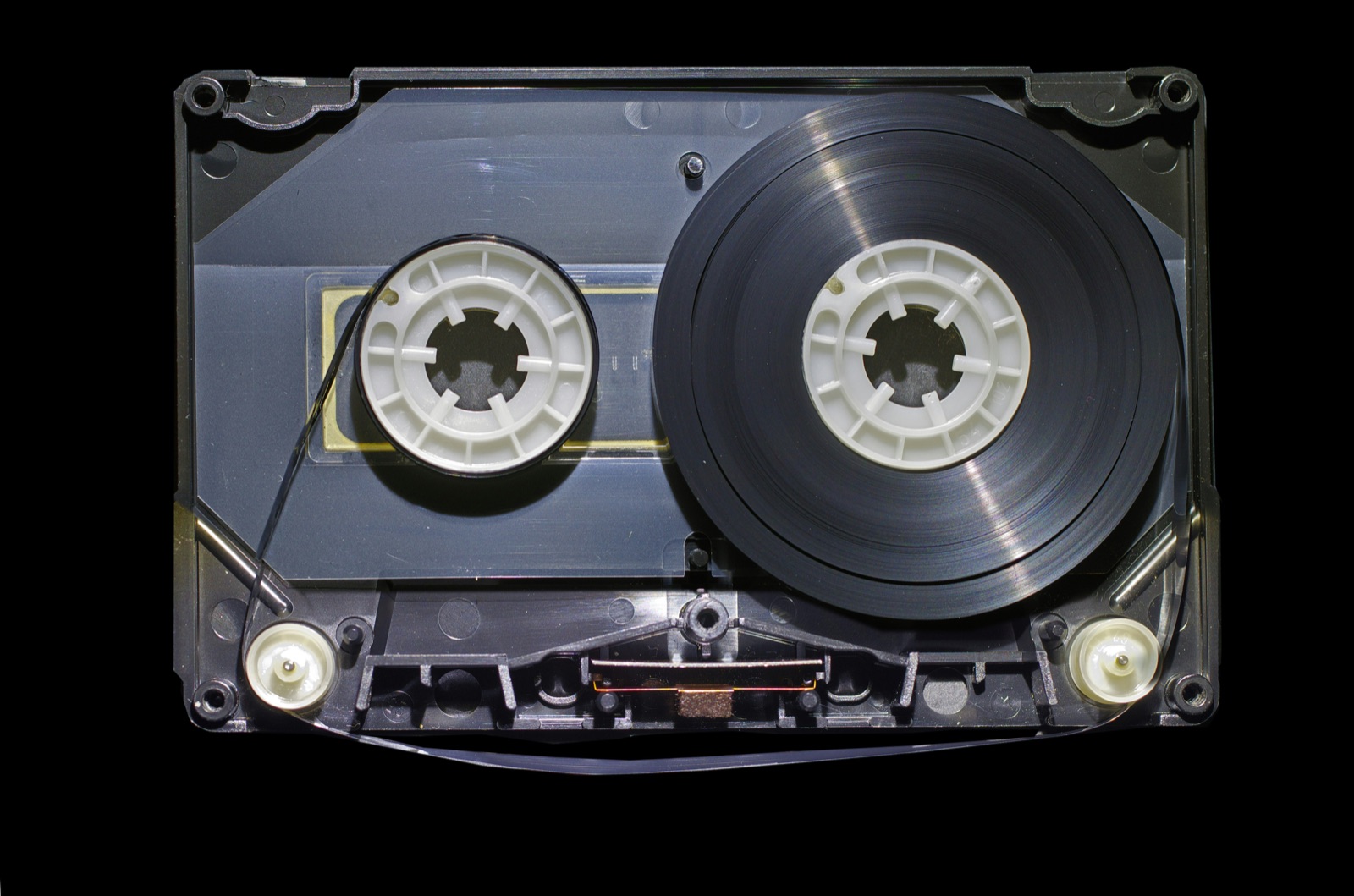 Close-up of a vintage audio cassette tape internals against a black background