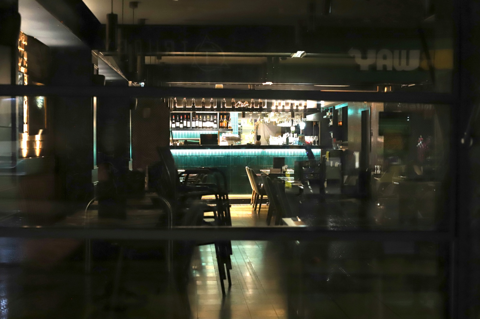 Dimly lit bar interior with glowing counter and moody atmospheric lighting, empty of patrons