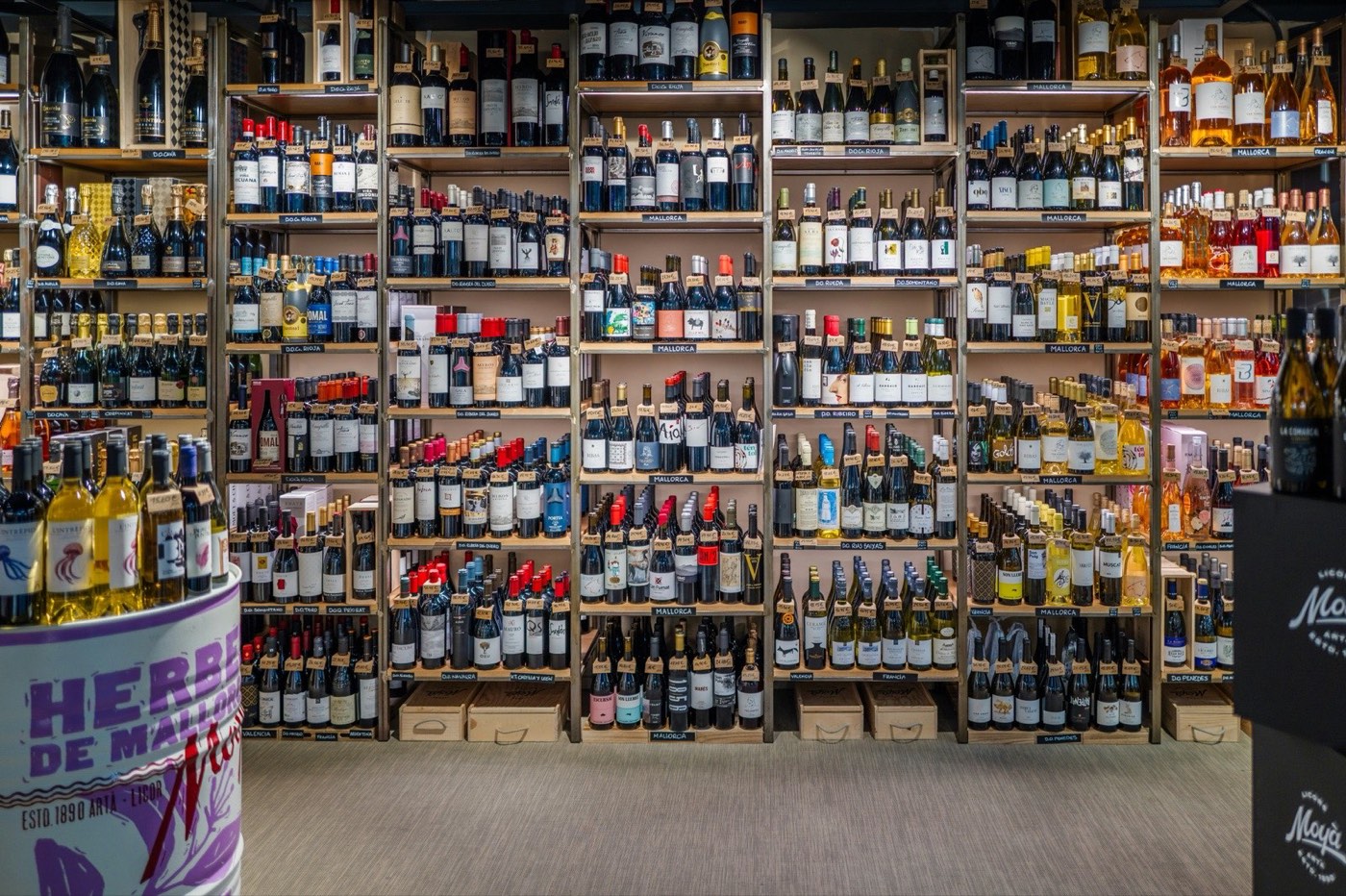 Rows of wine bottles arranged on retail store shelves, showing French and European wines in a well-lit shop interior