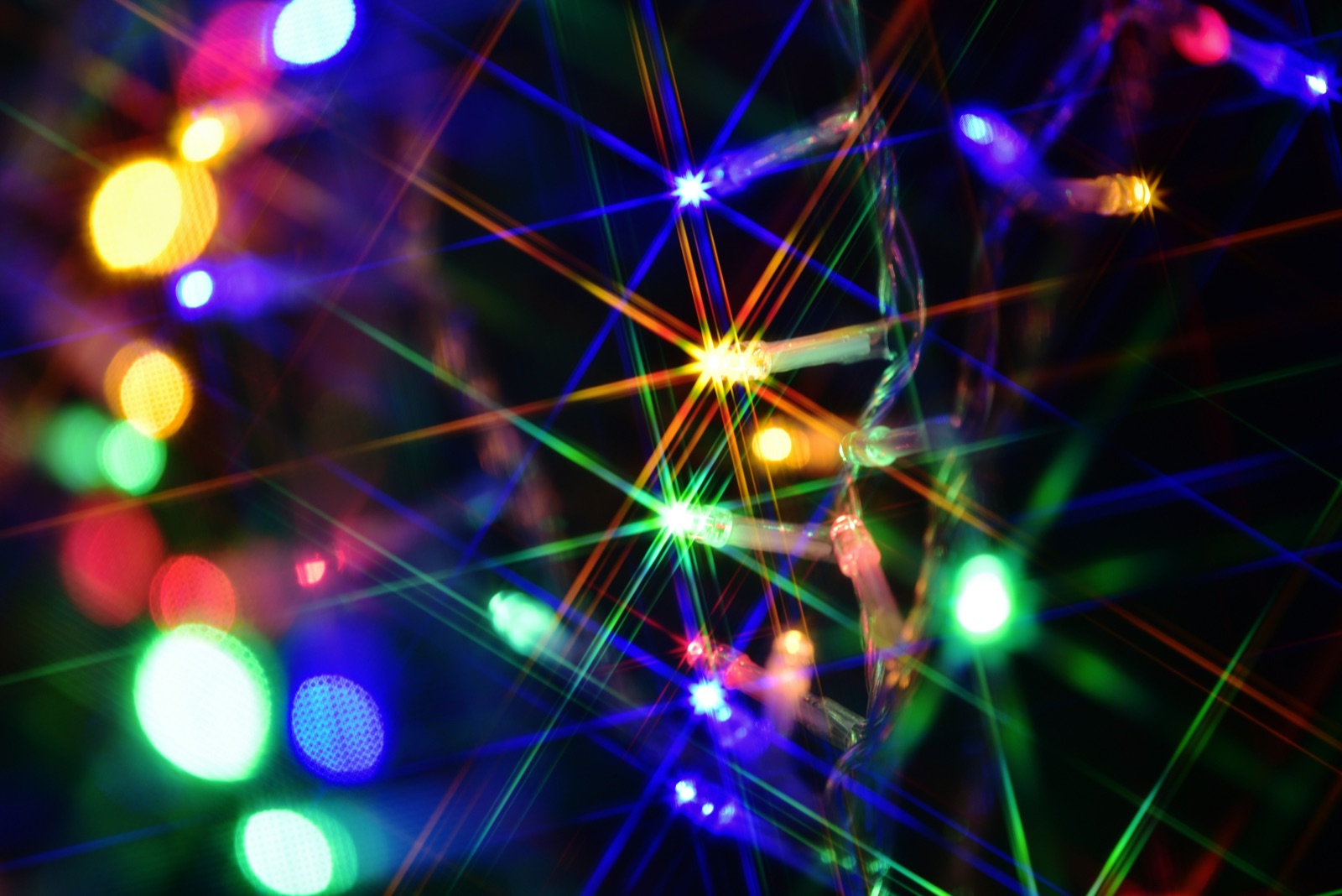 Colorful Christmas lights in close-up with starburst effects against a dark background
